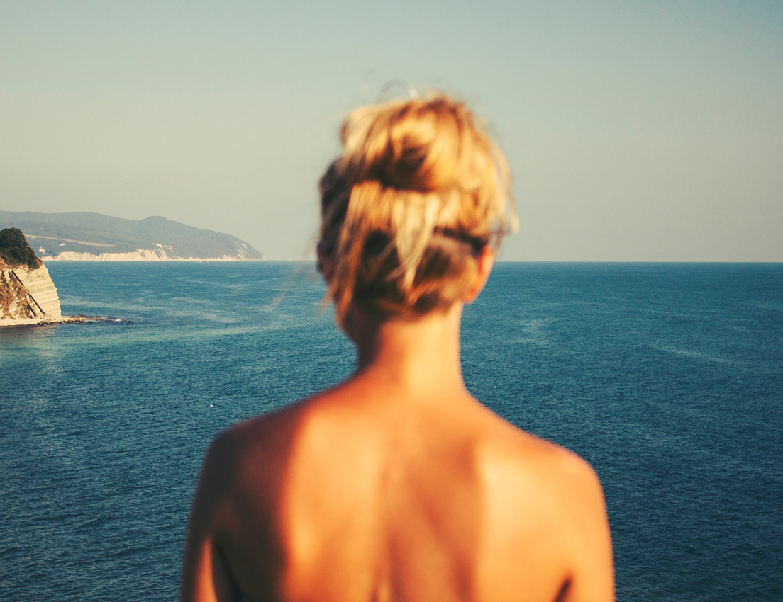 Imagen de una mujer de espaldas con el pelo recogido mirando el mar