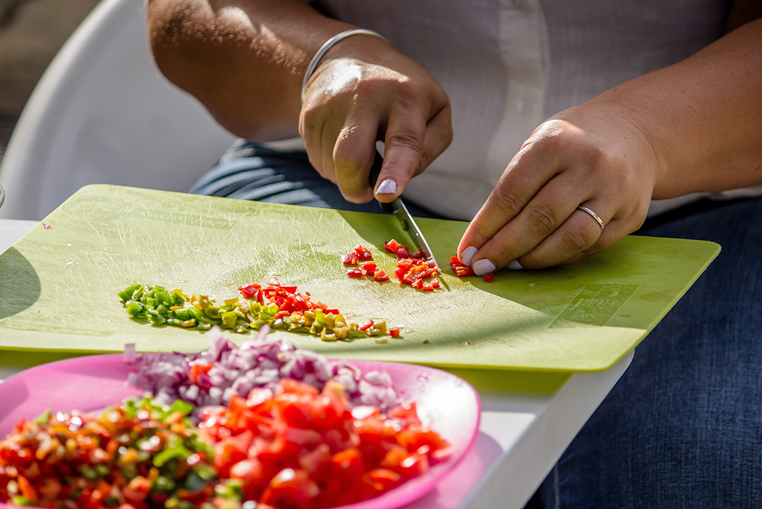 Imagen de persona picando con un cuchillo diferentes verduras sobre tabla de cortar.