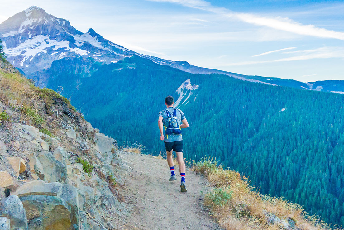 Hombre corriendo por la senda con una vista de una montaña